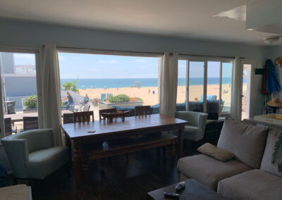 inside living room at a beach house with a comfy L shaped sofa and dining table and ocean view with hardwood floors