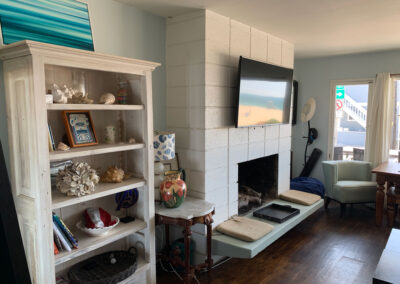 inside living room at a beach house with a fireplace and a tv above it 
